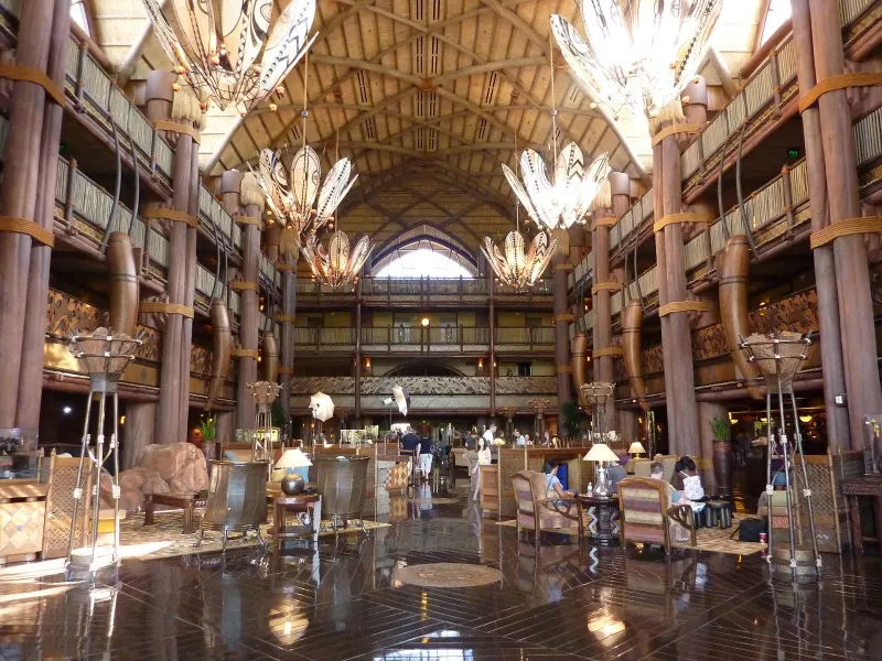 The multi-story lobby of Jambo House at Disney's Animal Kingdom Lodge, with wooden columns, balconies and large African-inspired chandeliers
