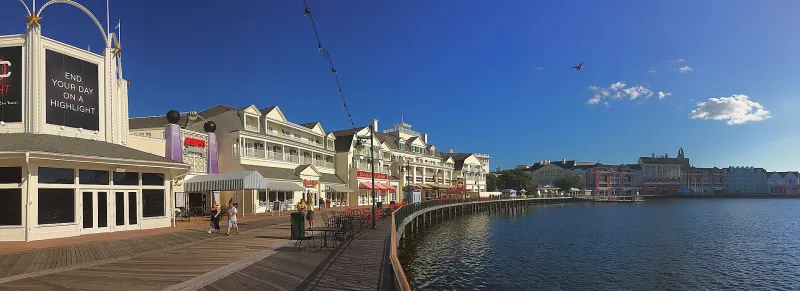 Disney's BoardWalk promenade along Crescent Lake, lined with seaside-style buildings under a blue sky