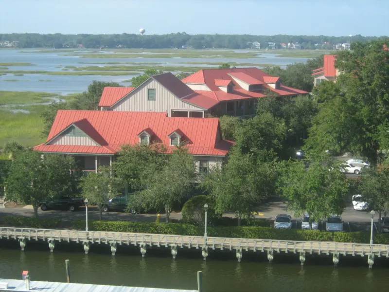 Red-roofed buildings of Disney's Hilton Head Island Resort among trees beside the salt marsh, with a waterfront boardwalk in front