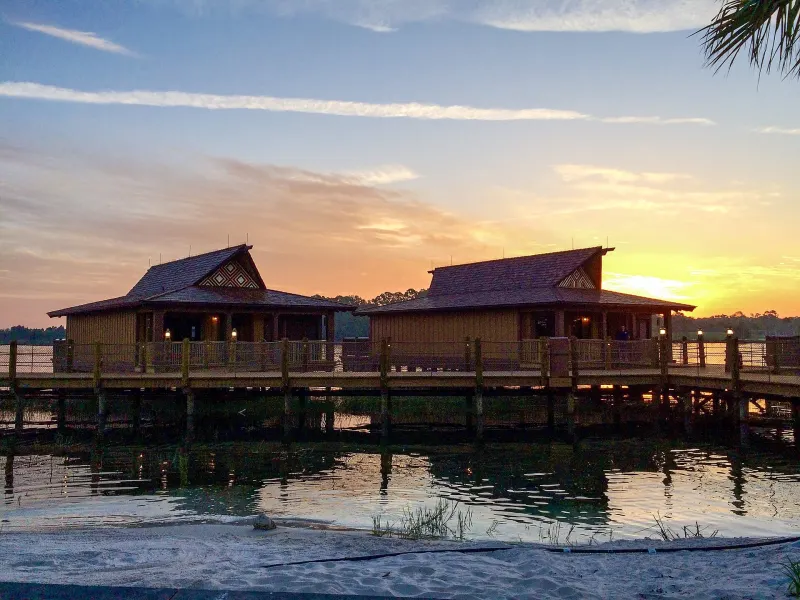 The Polynesian's overwater Bora Bora Bungalows on Seven Seas Lagoon under a colorful sunrise sky